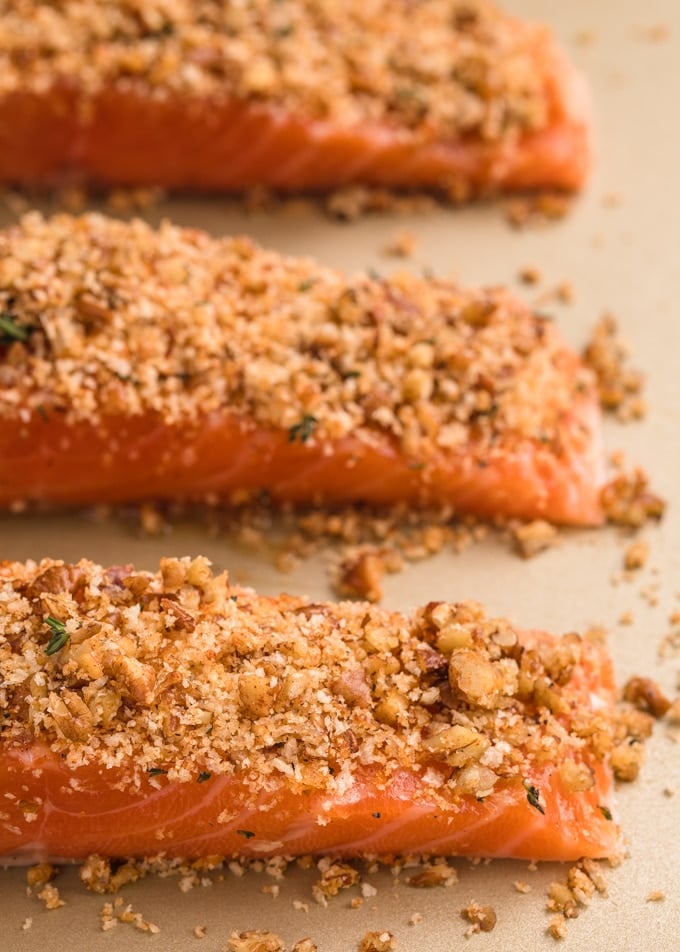 raw salmon fillets on a baking sheet with pecan and panko crust