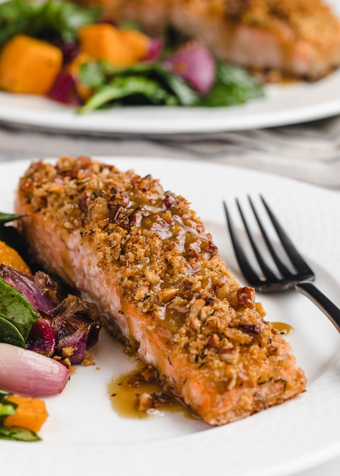 pecan crusted salmon on a white plate with baby spinach and roasted butternut squash