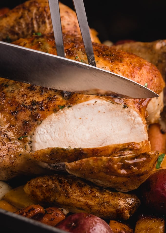 slicing roasted chicken breast with a carving knife and fork