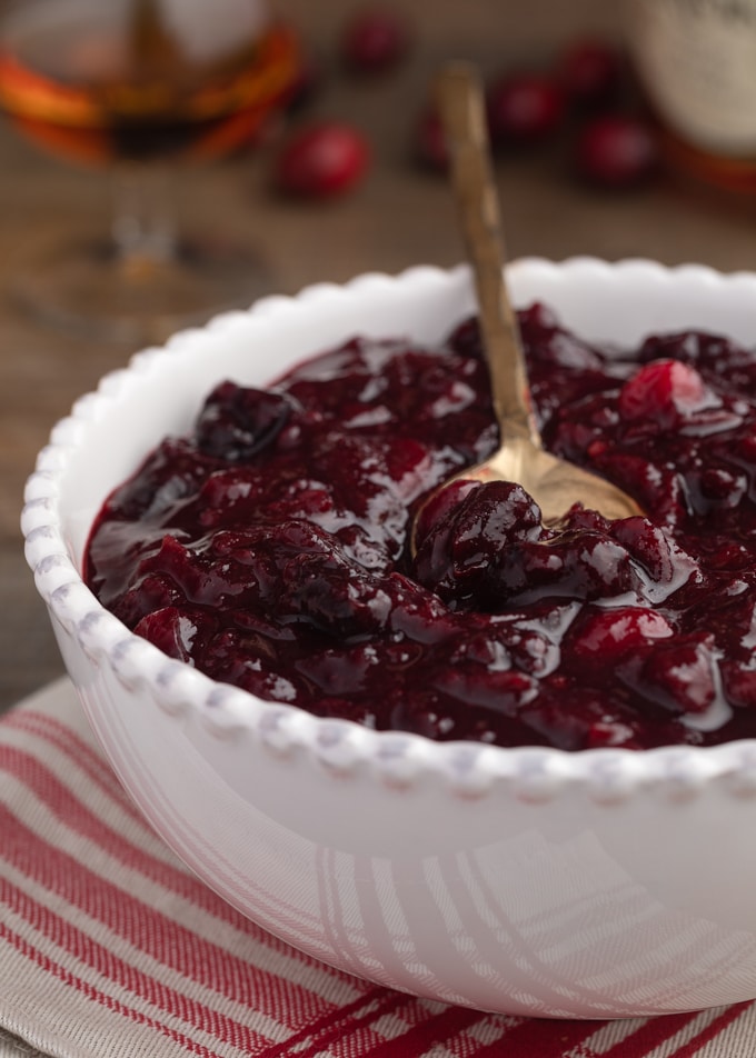 cherry cranberry sauce with brandy in a white ceramic bowl on a red striped napkin