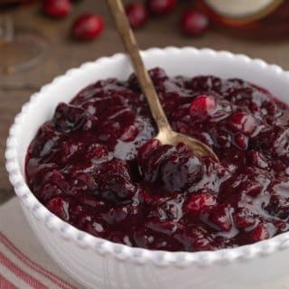 brandied cherry cranberry sauce in a white bowl with a gold spoon