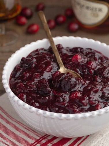 brandied cherry cranberry sauce in a white bowl with a gold spoon