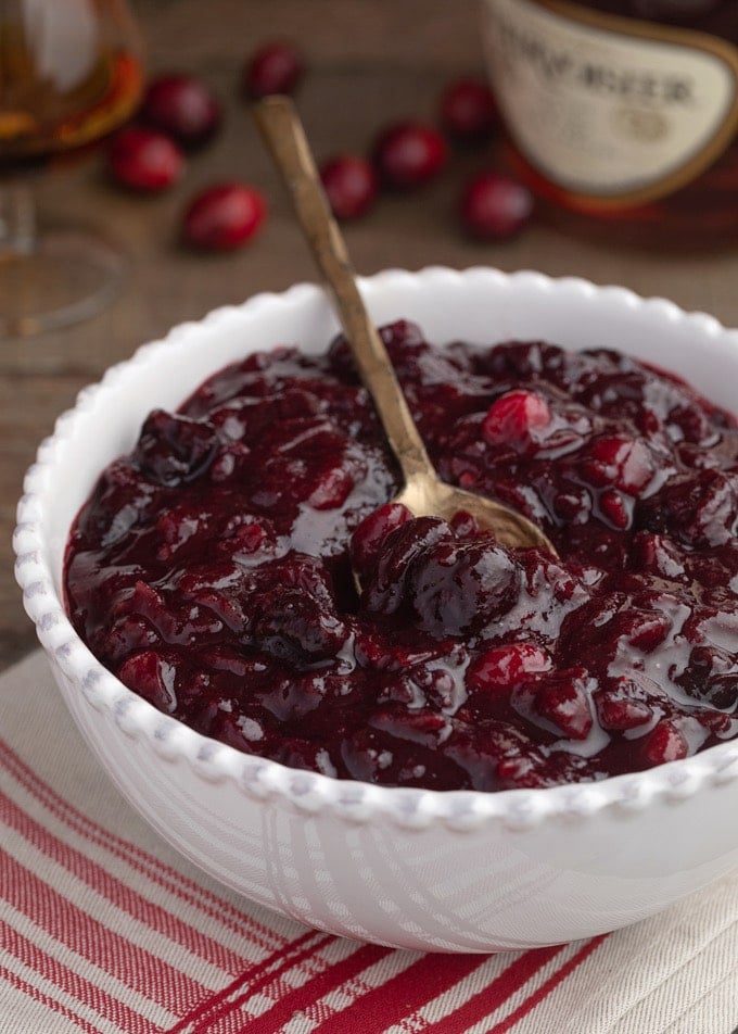 brandied cherry cranberry sauce in a white bowl with a gold spoon