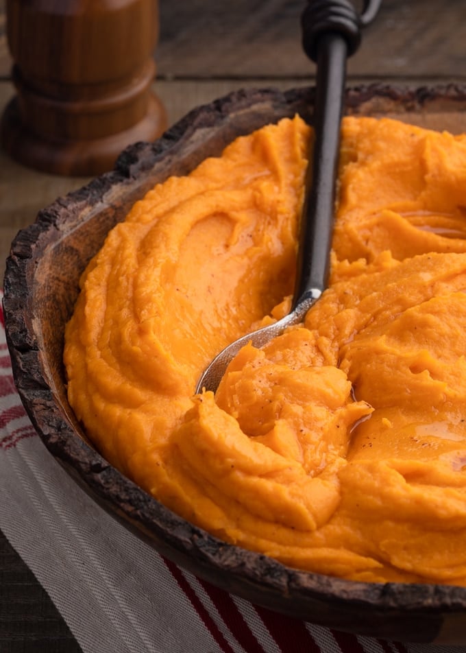 brown butter whipped sweet potatoes in a wooden bowl with a serving spoon