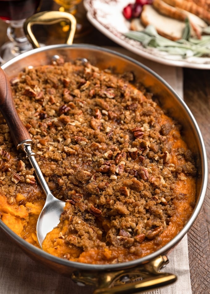 buttermilk sweet potato casserole in a copper gratin dish with a serving spoon