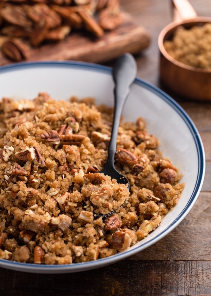 pecan streusel topping in a white and blue bowl with a black spoon