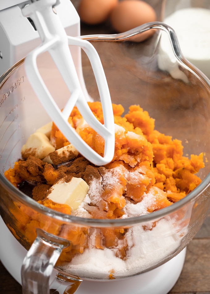 sweet potatoes in a white stand mixer with butter, sugar, and cinnamon