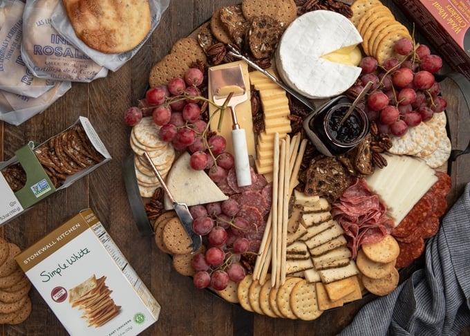 assembled cheese board next to boxes of artisan crackers