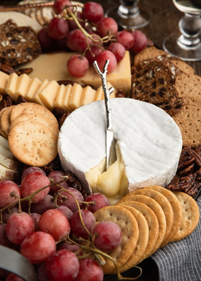 assorted crackers and cheeses with grapes on a wood board