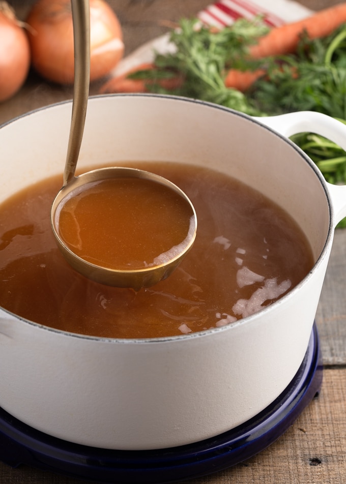 ladleful of hot turkey stock over a white pot