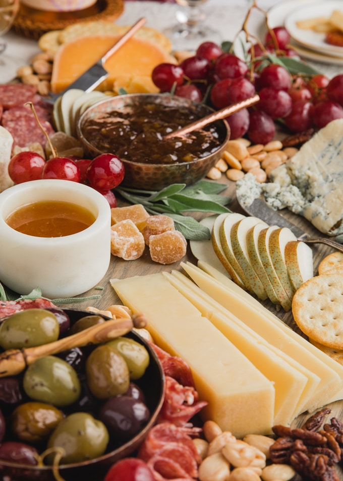 side view of a cheese board with assorted charcuterie, nuts, honey, fruit, and preserves