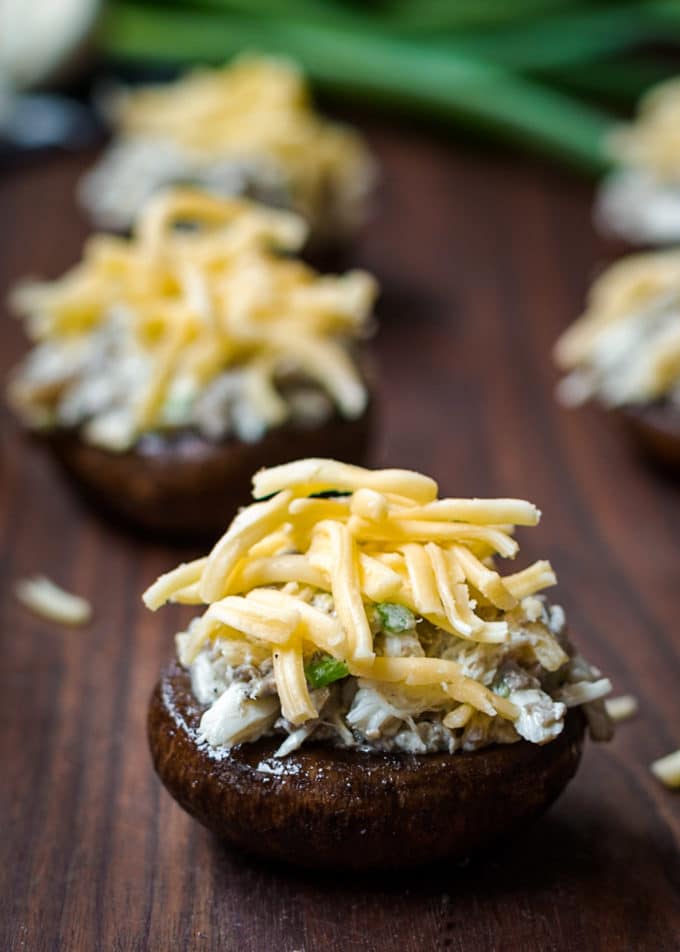 unbaked gouda and crab stuffed mushrooms on a wood cutting board