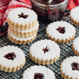 raspberry jam filled linzer cookies on a wire cooling rack