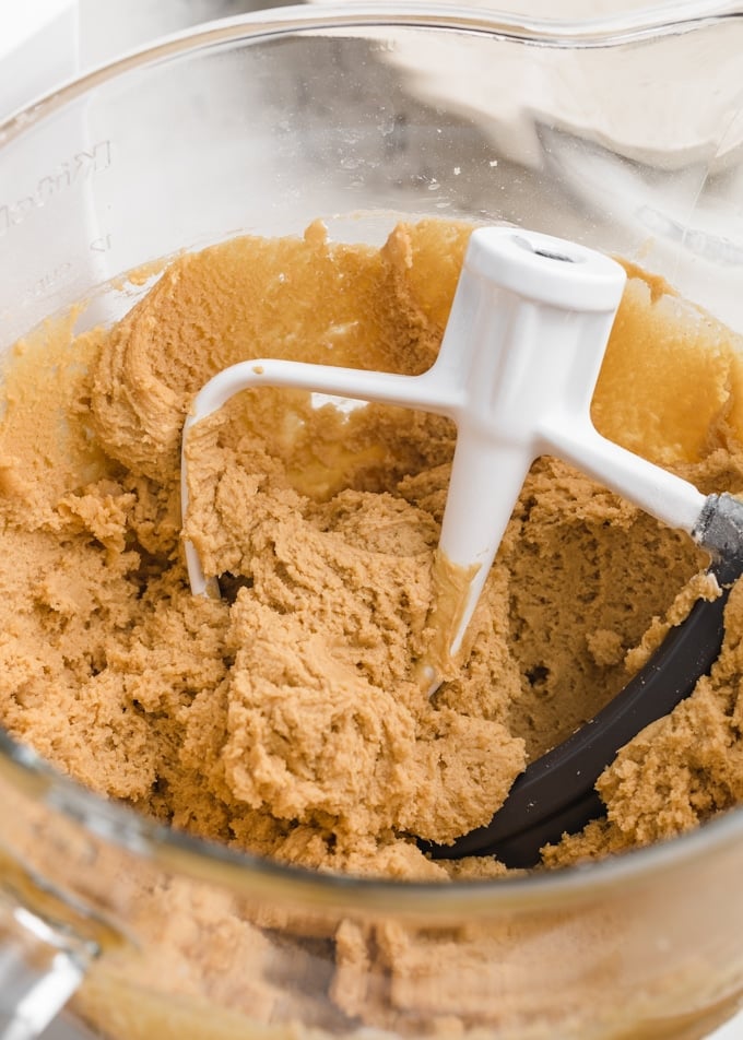 peanut butter blossom dough in the glass bowl of a stand mixer with the paddle attachment