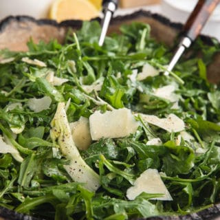 arugula salad with shaved fennel and parmigiano reggiano in a wooden serving bowl