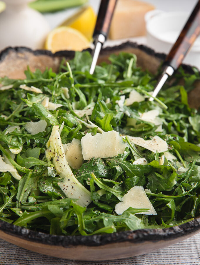 arugula salad with shaved fennel and parmigiano reggiano in a wooden serving bowl