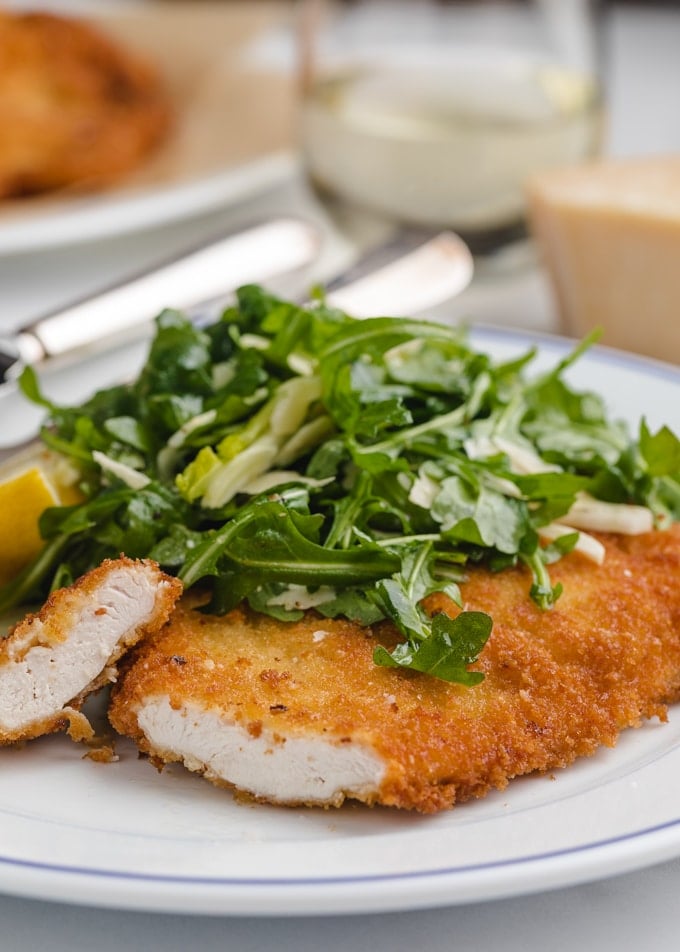 sliced chicken milanese cutlet on a white plate