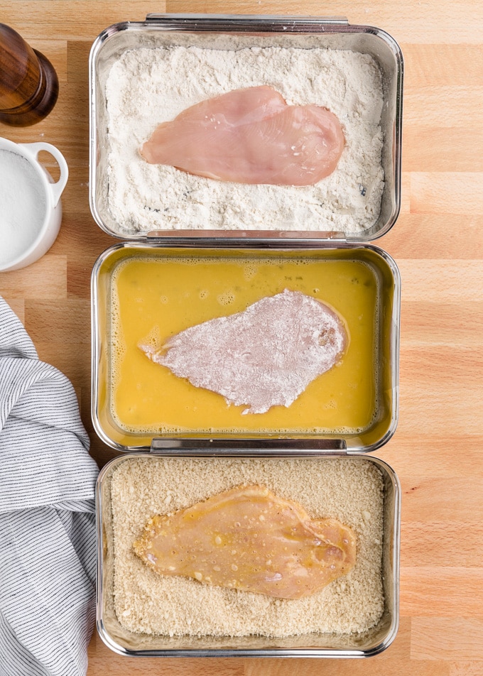 chicken cutlets in 3 breading trays: flour, egg wash, and panko breadcrumbs