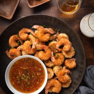 coconut shrimp on a bronze serving platter with spicy orange dipping sauce