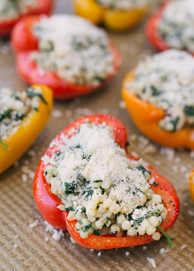 couscous stuffed peppers sprinkled with parmesan cheese on a baking sheet