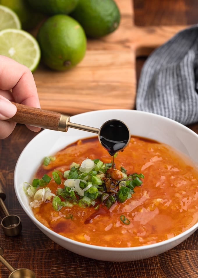 pouring soy sauce into a bowl of orange marmalade and scallions