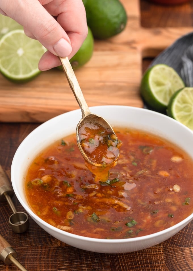 spoonful of orange dipping sauce being scooped from a white bowl