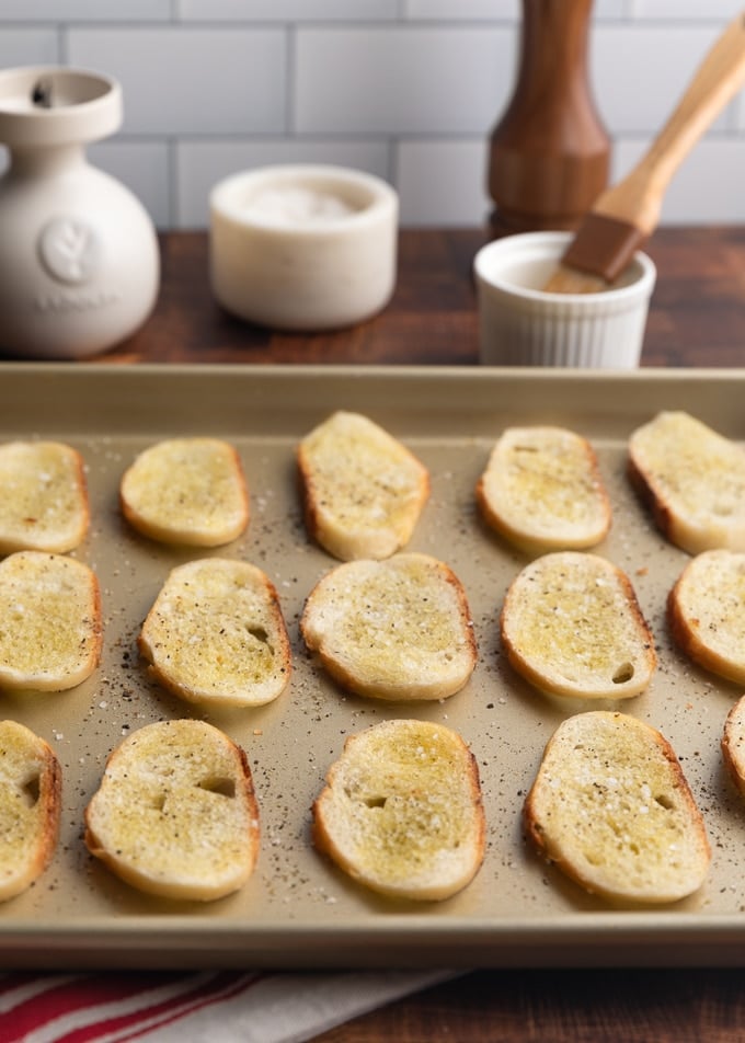 pan of crostini toasts with olive oil, salt, and pepper