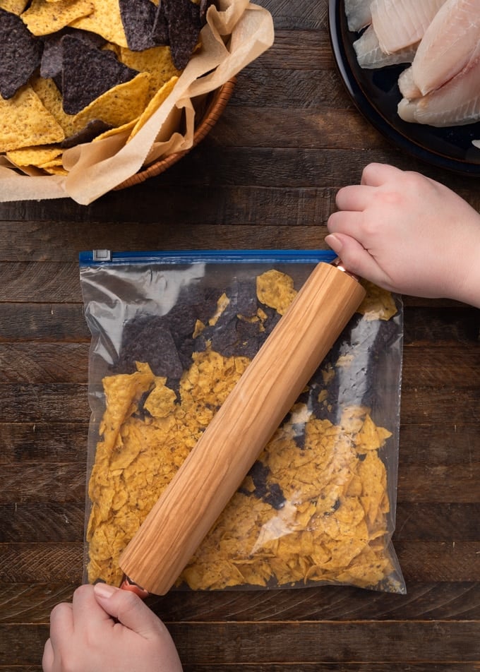 crushing tortilla chips in a plastic bag with a rolling pin