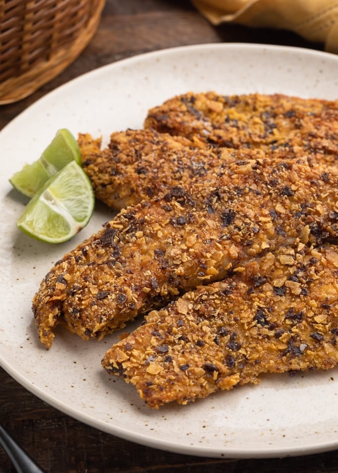 pan-fried tortilla chip breaded tilapia fillets on an ivory plate