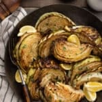 roasted cabbage with lemon wedges in a dark bronze serving bowl