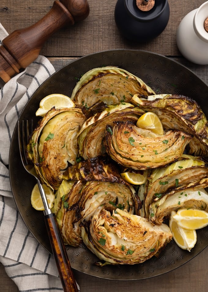 roasted cabbage with lemon wedges in a dark bronze serving bowl