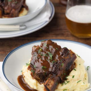 stout beer braised short rib in a white serving bowl over mashed potatoes