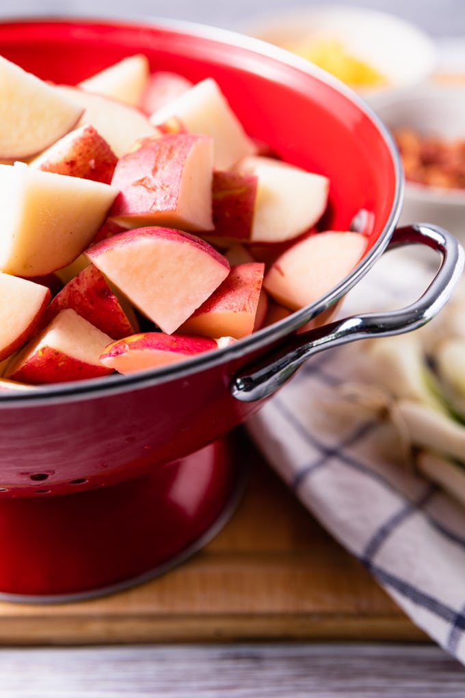 cubed raw red potatoes in a red colander