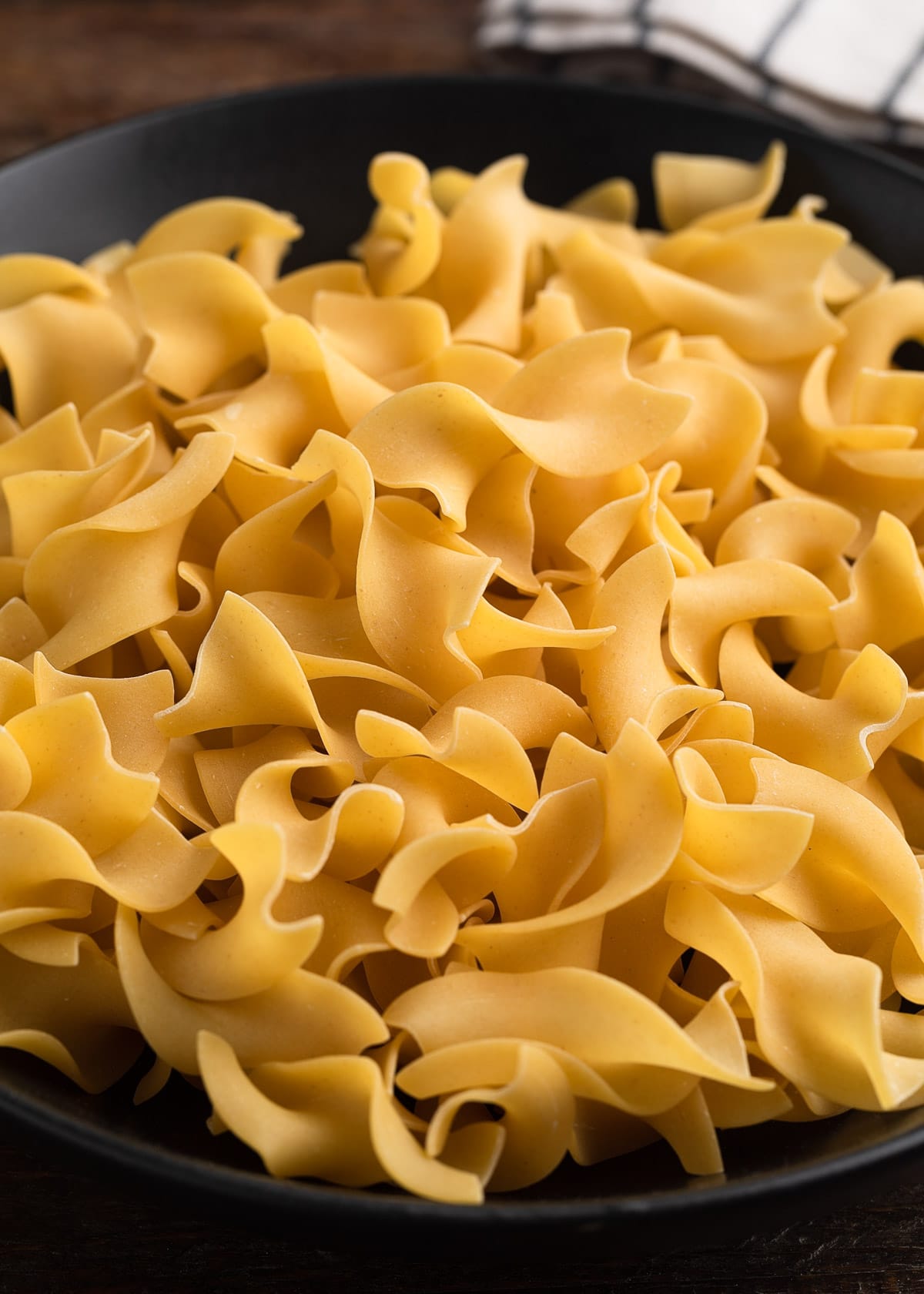 closeup of extra wide egg noodles in a bowl