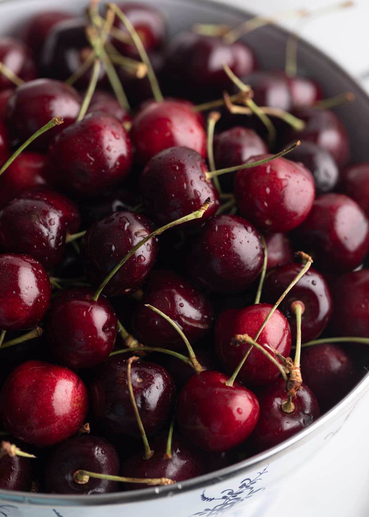 closeup photo of fresh Bing cherries in a white enameled colander