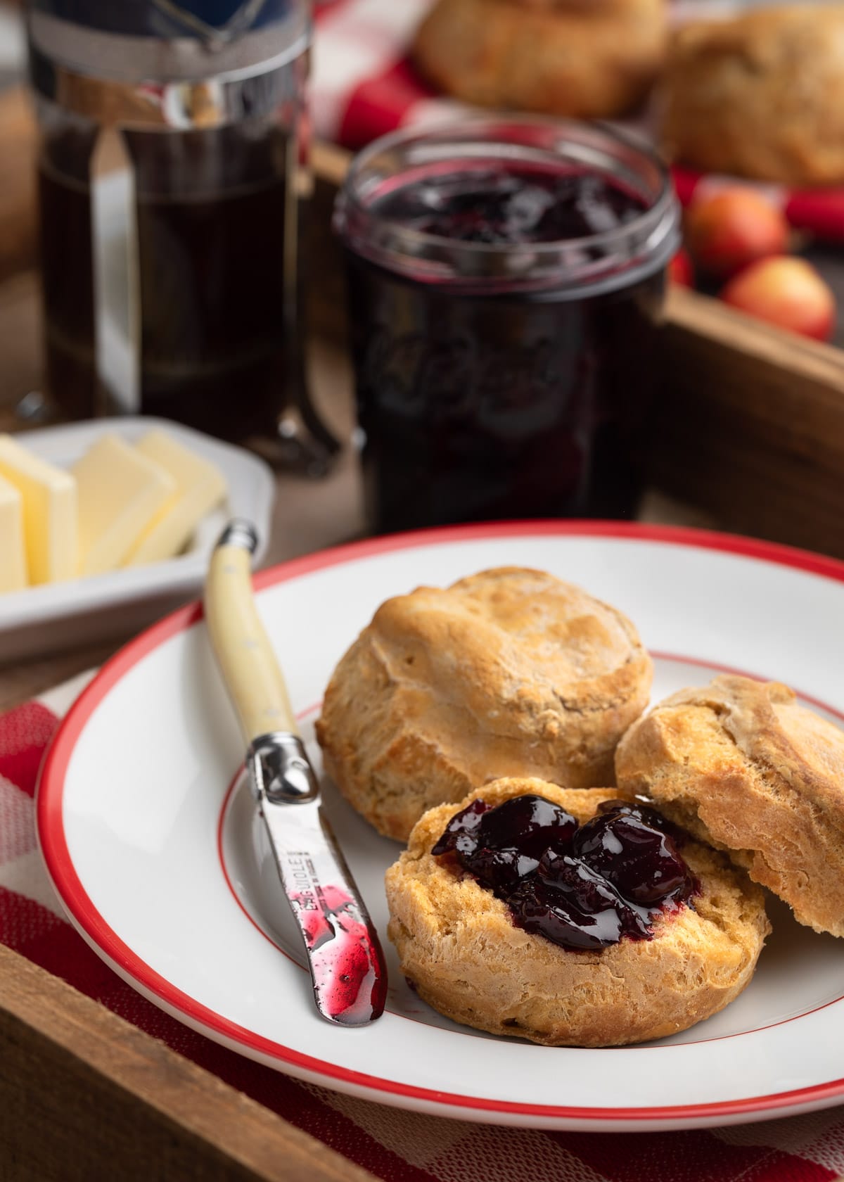 homemade cherry preserves on a sweet potato biscuit, on a red-rimmed white plate, with a spreading knife