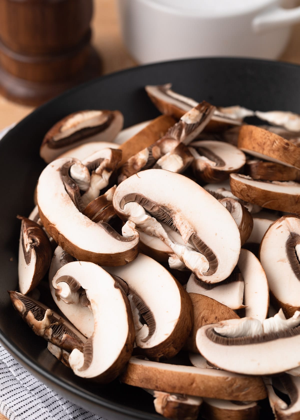 sliced cremini mushrooms in a dark gray matte bowl