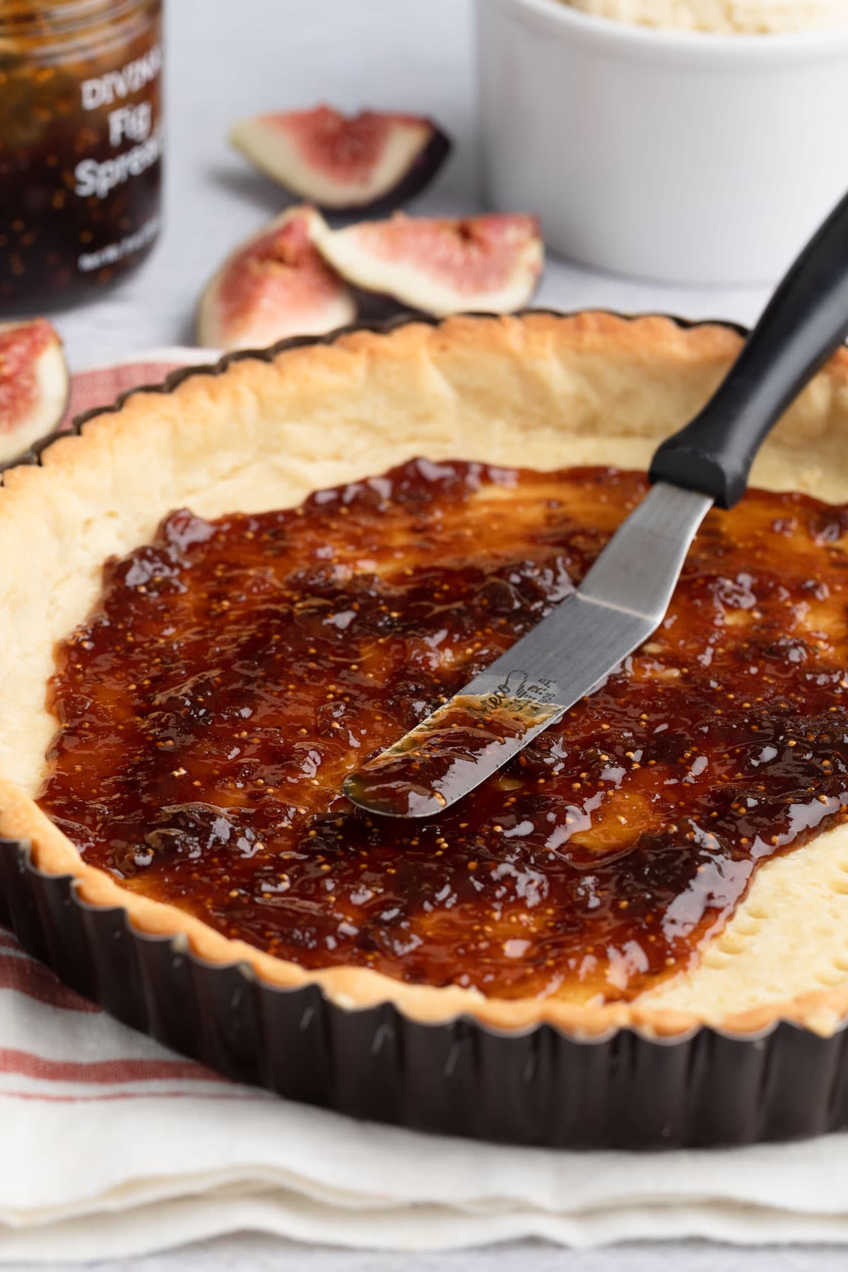 fig spread in a par-baked tart shell with a metal spreader