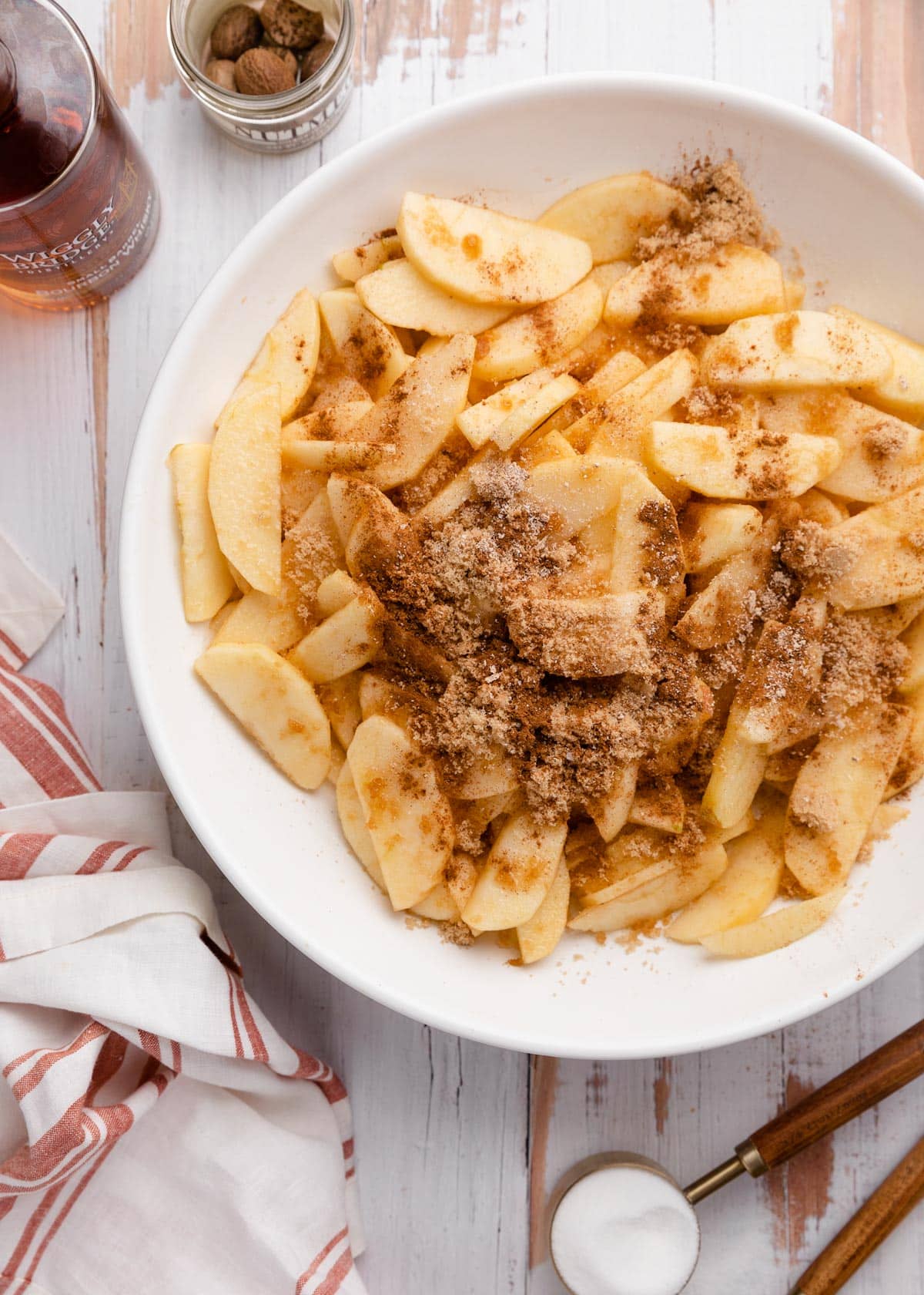 sliced honeycrisp apples in a white bowl with cinnamon and brown sugar