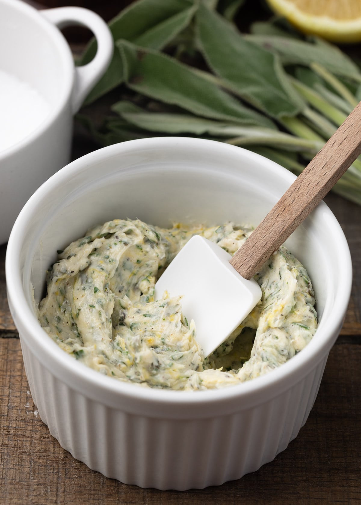 herb compound butter in a white ramekin with a small white spatula