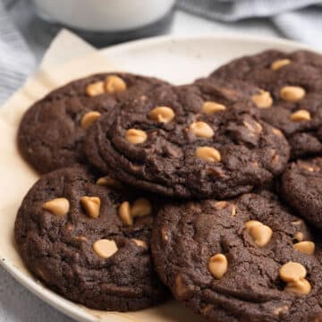 chocolate chip peanut butter cookies on a parchment lined dish with a glass of milk