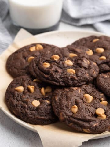 chocolate chip peanut butter cookies on a parchment lined dish with a glass of milk