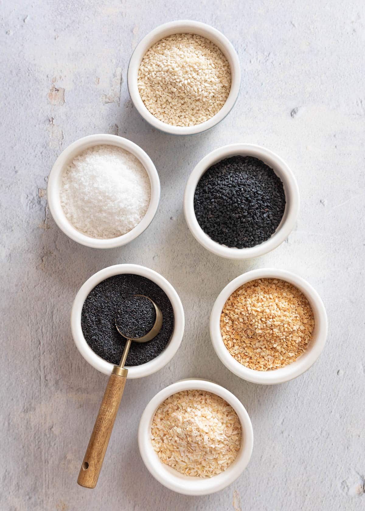 ingredients to make homemade everything bagel seasoning in ceramic bowls