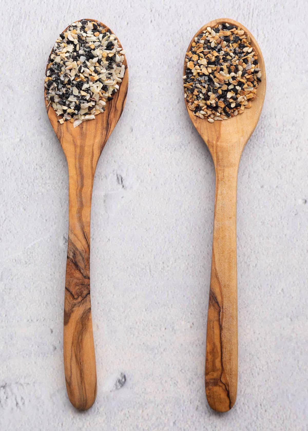 two olive wood spoons with untoasted and toasted everything seasoning