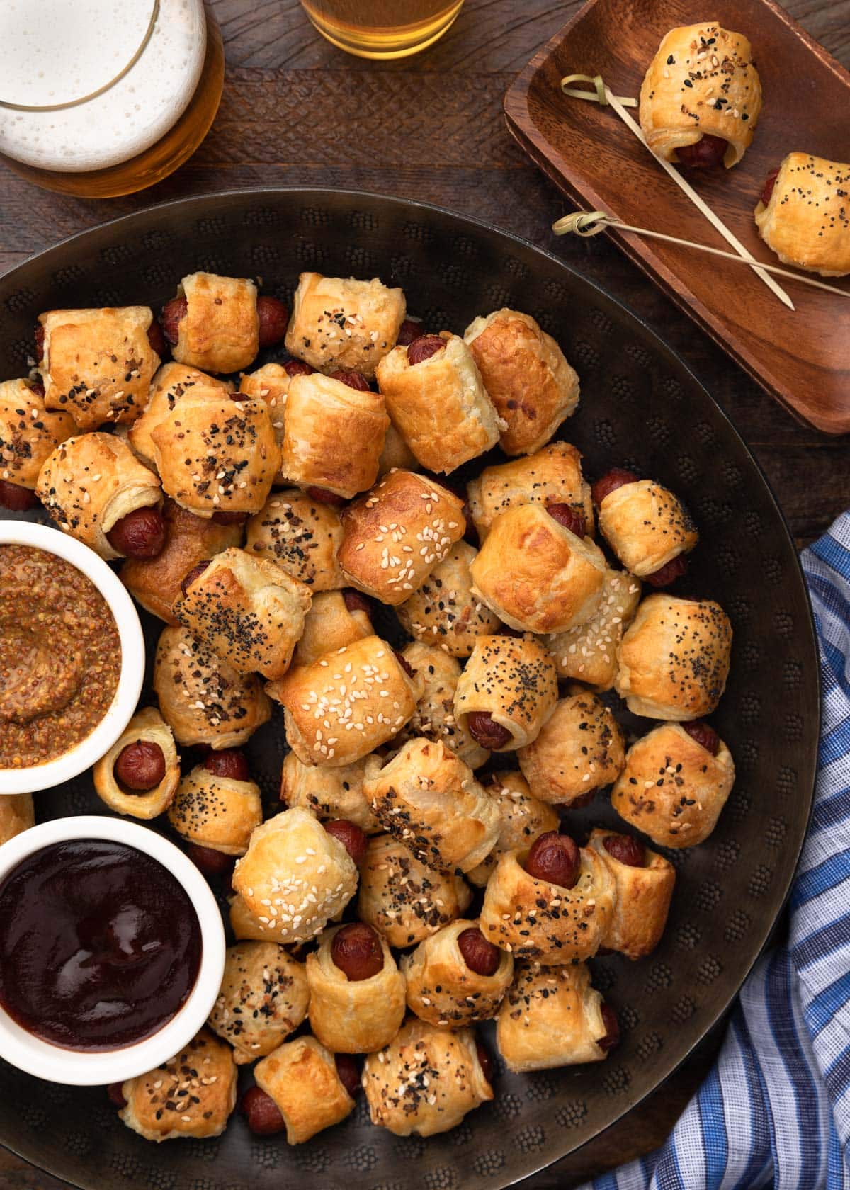 overhead of pigs in a blanket on a round serving platter with dipping sauces