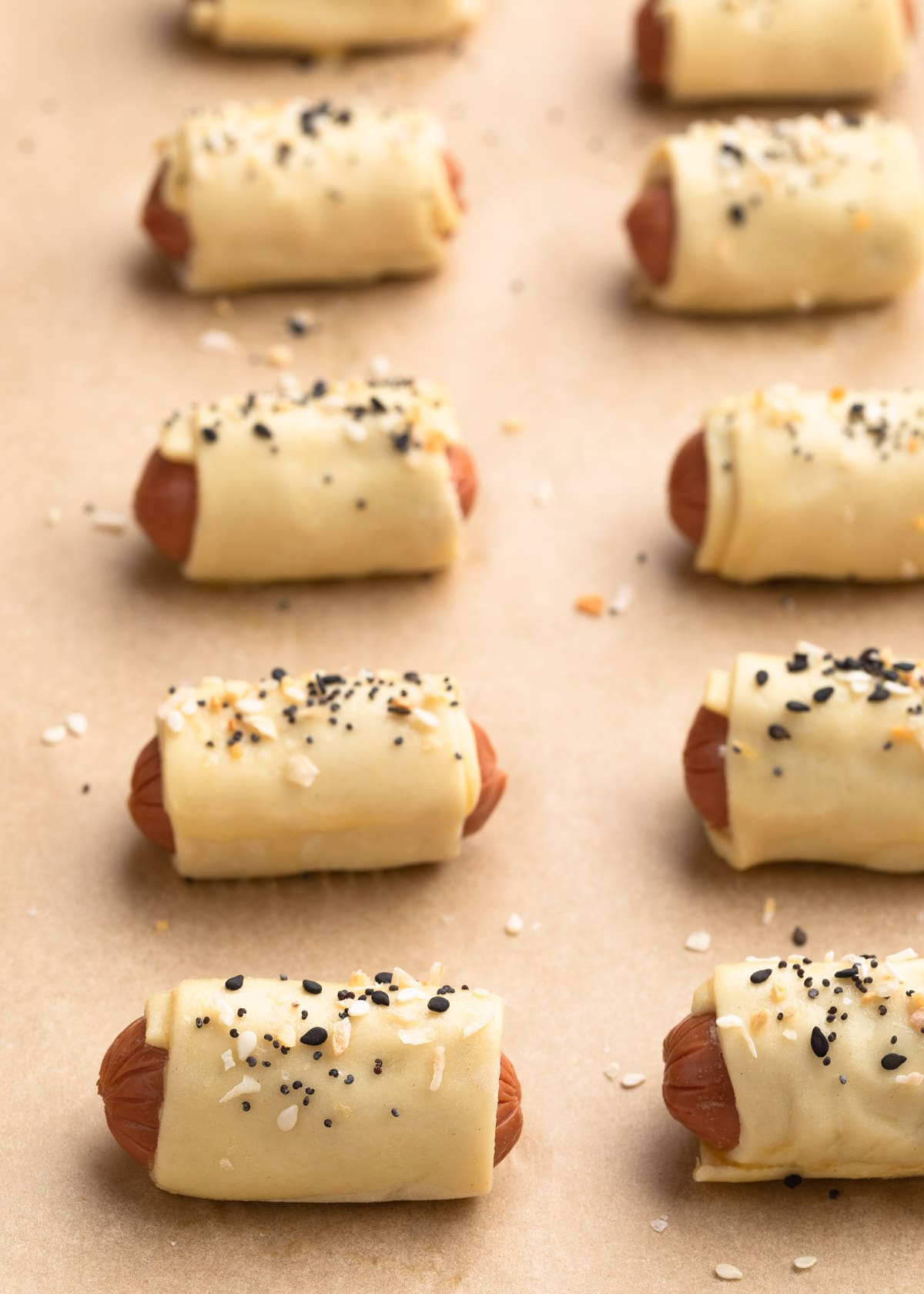 unbaked pigs in a blanket sprinkled with everything bagel seasoning on a parchment lined baking sheet