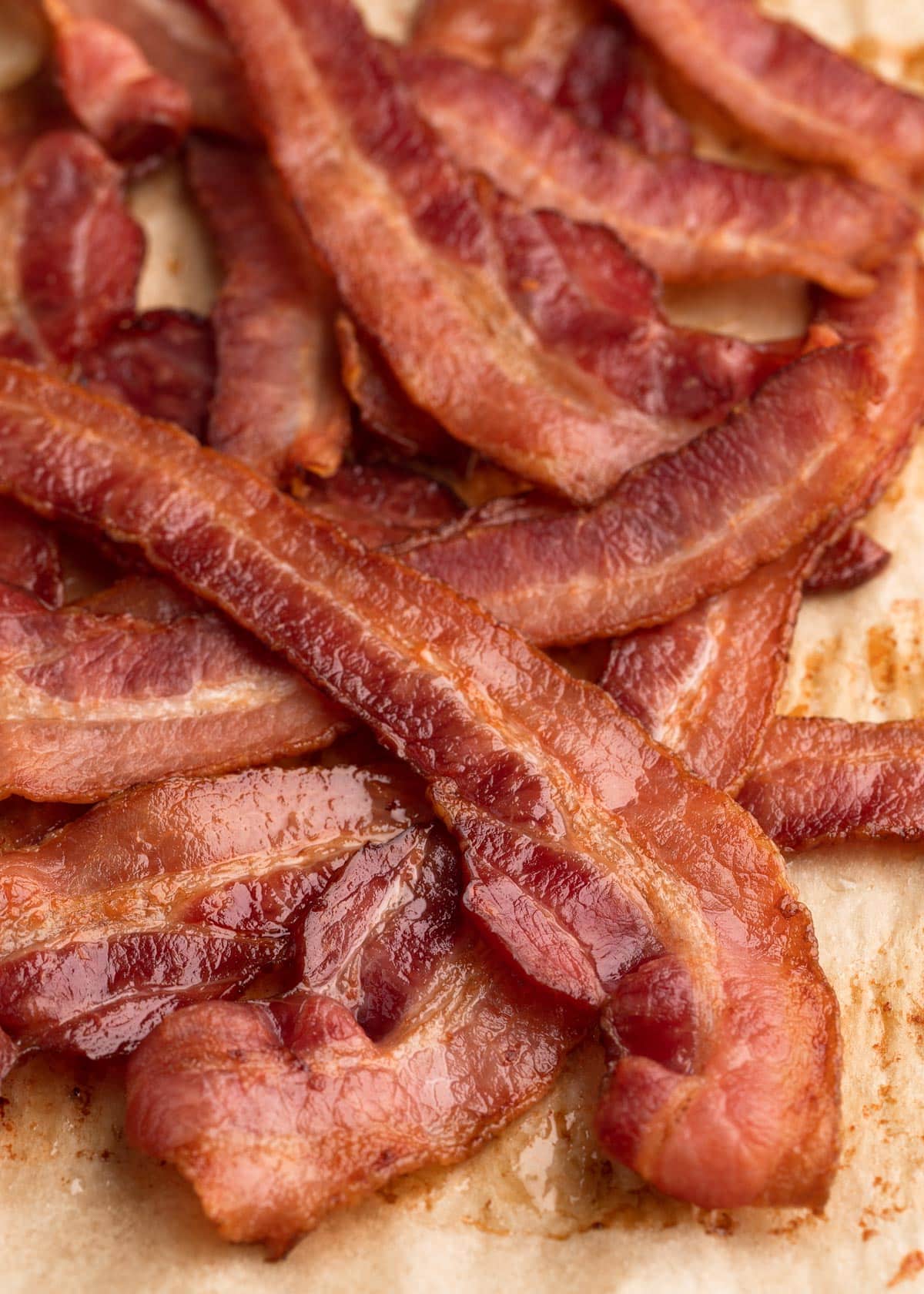 pile of baked bacon strips on a parchment-lined baking sheet