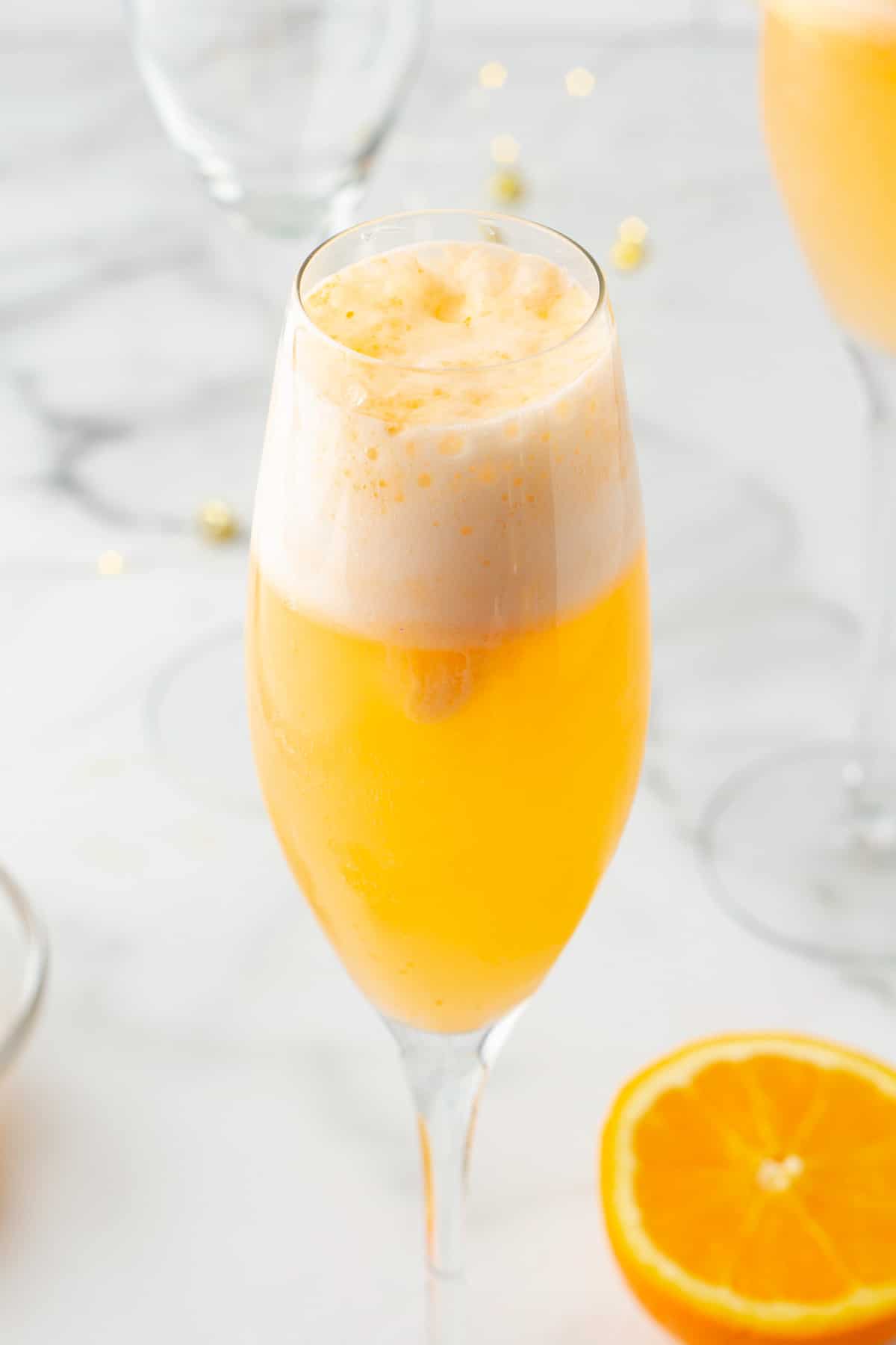 side view of an orange sherbet mimosa mocktail in a champagne flute