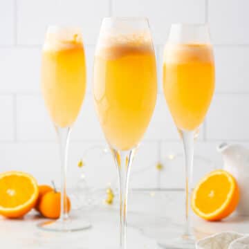 three orange sherbet mimosa mocktails in champagne flutes