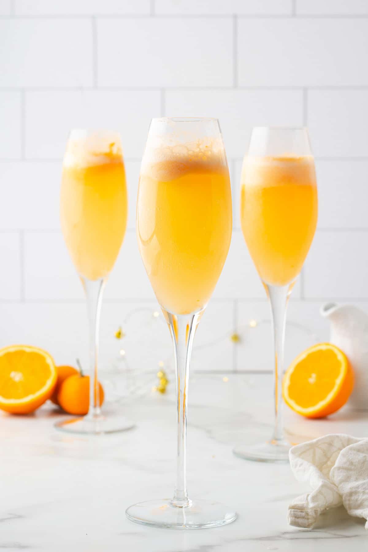 three orange sherbet mimosa mocktails in champagne flutes